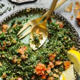 En fräsch tabbouleh med persilja, tomat och bulgur, serverad med citronklyftor och pitabröd. Ett perfekt tabbouleh recept för sommaren.
