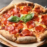 En utsökt pepperoni pizza med smält ost och färsk basilika. Vilken ost till pizza är din favorit?