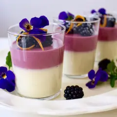 Tvåfärgade panna cotta med björnbär, apelsinzest och violer. En elegant dessert.