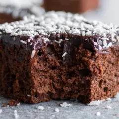 Saftig chokladkaka recept: en bit mörk chokladkaka med chokladglasyr och kokosflingor.