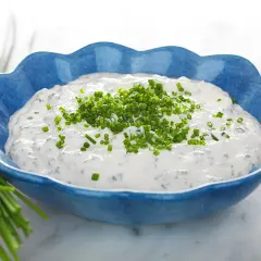 Kall sås till paj, en krämig gräddfilssås med gräslök, serverad i en blå skål.