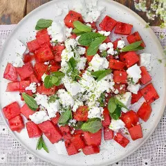 Watermelon and feta salad with mint and lime zest on a white plate.