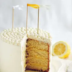 Tårta med fluffig frosting och lager av saftig sockerkaka fylld med syrlig lemon curd. En citronskiva ligger bredvid.