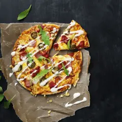 En läcker tortilla pizza med jalapeños, skinka och ruccola, ringlad med vit sås.
