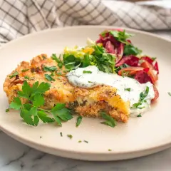 En bit saftig skinkpaj utan ost, toppad med färska örter och en klick krämig sås, serveras med en fräsch sallad.