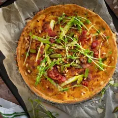 En gyllene sparrispaj med knaprigt bacon, pinjenötter och färska gröna toppar. Perfekt för en vårmåltid.