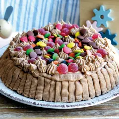 En härlig glutenfri tårta dekorerad med chokladfrosting och färgglada godisar, perfekt för barnkalas.