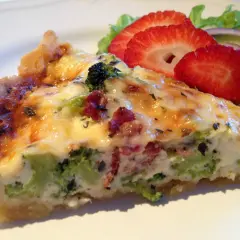 En bit broccoli och baconpaj med en sallad på sidan. Pajen har en gyllene skorpa och fyllning med broccoli och bacon.