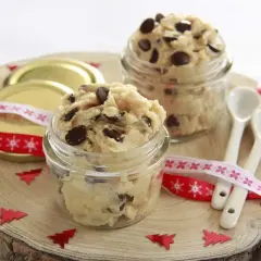 Två glasburkar fyllda med ljuvlig cookie dough, perfekt för ett enkelt cookie dough recept. Julpynt och små skedar ligger redo.