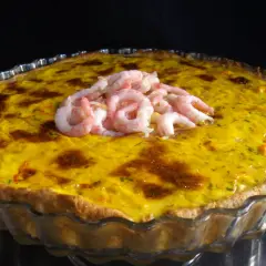 En gyllene räkpaj med en generös topping av saftiga räkor, redo att avnjutas.