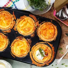 Nybakade minipajer med ost i en muffinsform. En burk ansjovis och lite gräddfil står bredvid.