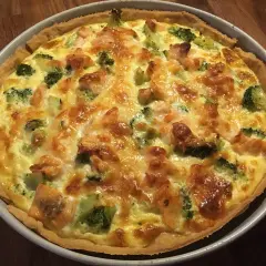 En gyllene laxpaj med broccoli och smält ost, redo att serveras.