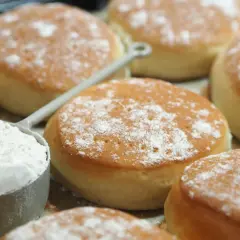 Nybakade tekakor, pudrade med mjöl, redo för ett enkelt tekakor recept. En skopa mjöl syns i förgrunden.