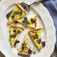 Läckra bitar av paj utan ost, garnerade med färska örter och mörklila blad, serverade på en vit tallrik.