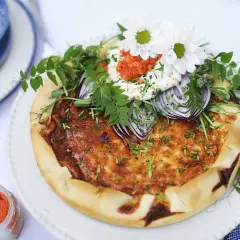 En vackert dekorerad Västerbottenpaj med romsås, rödlök, örter och blommor. Perfekt för en festlig måltid.