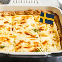 En gyllene västerbottenpaj till många, dekorerad med en svensk flagga och rosmarin. Perfekt för firande!