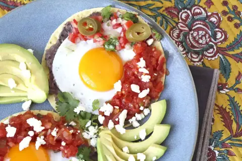 Två huevos rancheros med stekt ägg, svarta bönor, salsa, jalapeños och avokado. En härlig frukost!
