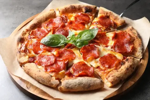 En utsökt pepperoni pizza med smält ost och färsk basilika. Vilken ost till pizza är din favorit?
