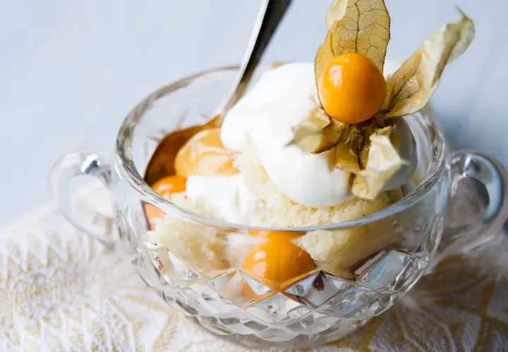 En härlig lemoncurd tårta i en kristallskål, toppad med grädde och physalis. En dröm för alla sötsugna!