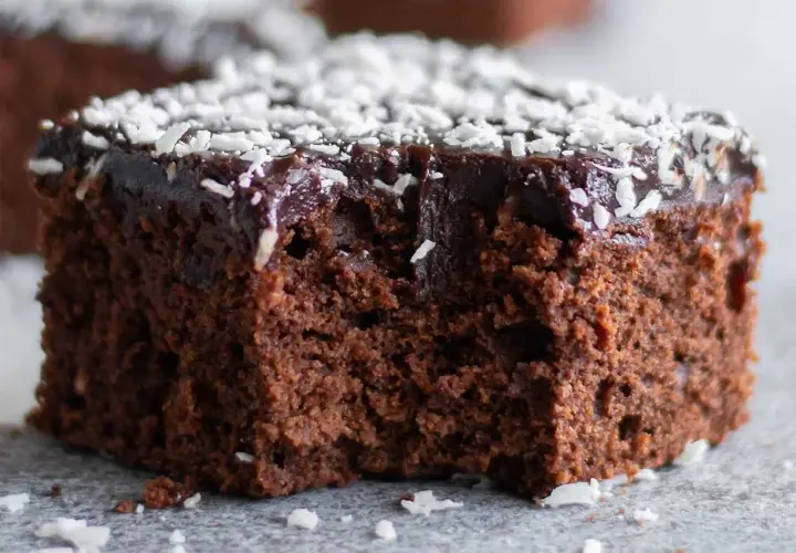 Saftig chokladkaka recept: en bit mörk chokladkaka med chokladglasyr och kokosflingor.