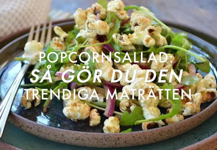 A close-up of a popcorn salad with greens and red onion on a dark plate, with a fork.