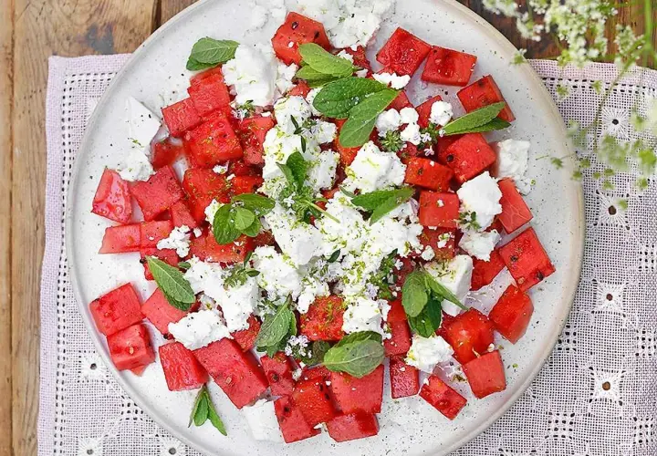 Watermelon and feta salad with mint and lime zest on a white plate.
