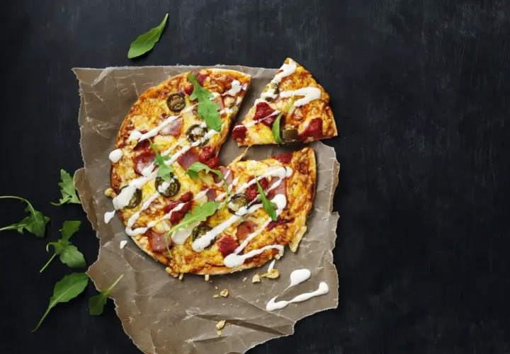 En läcker tortilla pizza med jalapeños, skinka och ruccola, ringlad med vit sås.