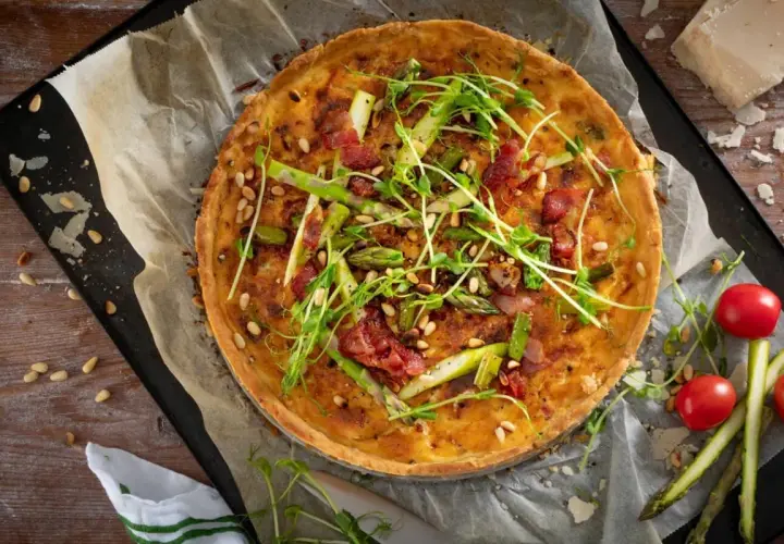 En gyllene sparrispaj med knaprigt bacon, pinjenötter och färska gröna toppar. Perfekt för en vårmåltid.