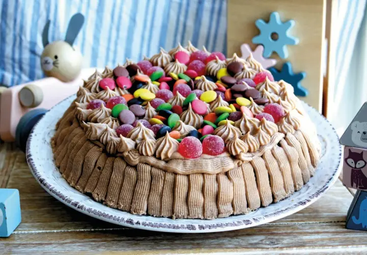 En härlig glutenfri tårta dekorerad med chokladfrosting och färgglada godisar, perfekt för barnkalas.