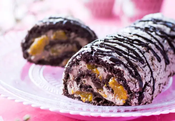 En chokladkaka med aprikosfyllning, perfekt för ett budapestrulle recept. Garnerad med chokladsås och pudersocker.