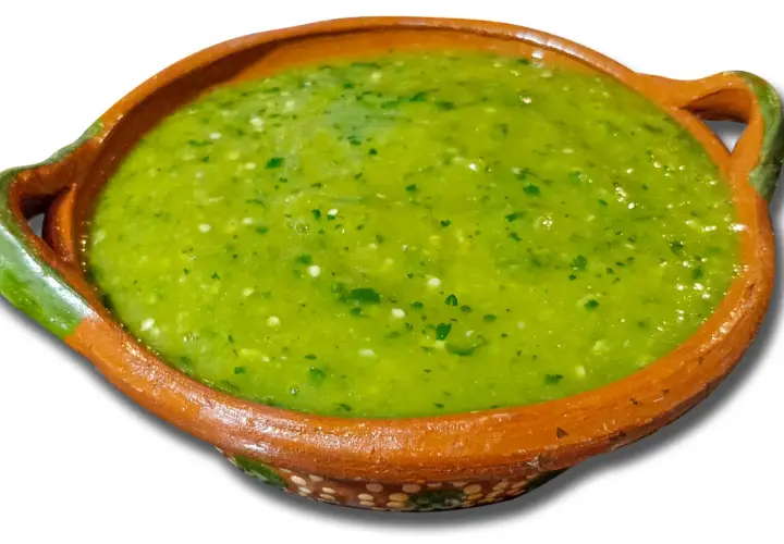 A bowl of vibrant green salsa with visible cilantro and chili pieces.