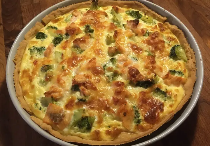 En gyllene laxpaj med broccoli och smält ost, redo att serveras.