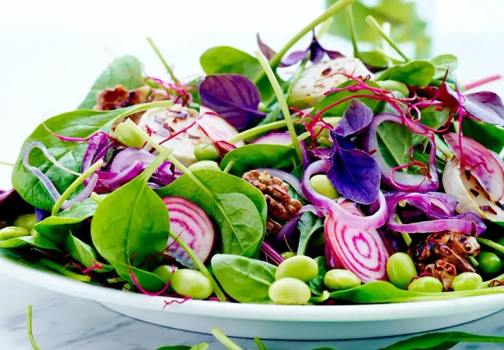 En färgglad sallad med spenat, rödlök, edamamebönor och valnötter. Perfekt som en lätt lunch, och ja, man kan värma spenat till den!
