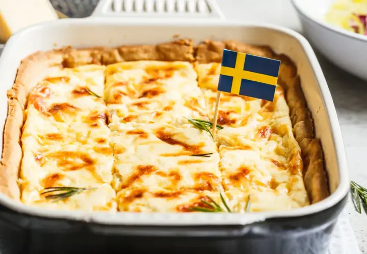 En gyllene västerbottenpaj till många, dekorerad med en svensk flagga och rosmarin. Perfekt för firande!