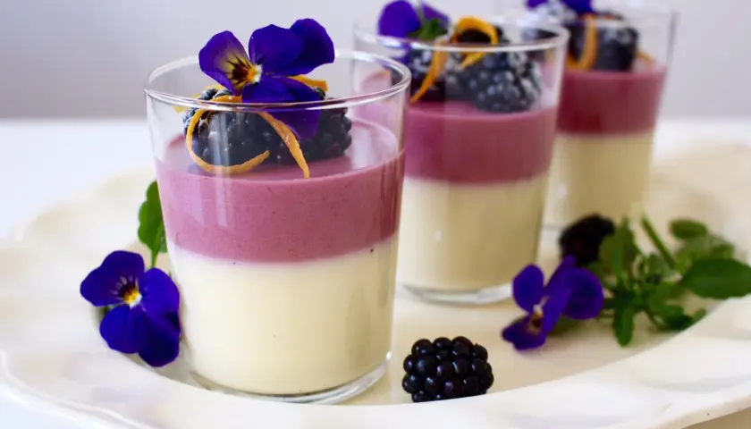 Tvåfärgade panna cotta med björnbär, apelsinzest och violer. En elegant dessert.