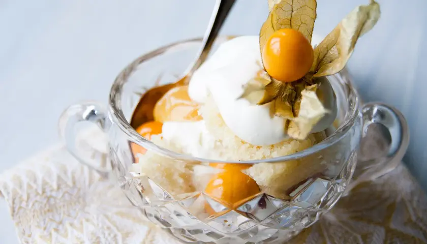 En härlig lemoncurd tårta i en kristallskål, toppad med grädde och physalis. En dröm för alla sötsugna!