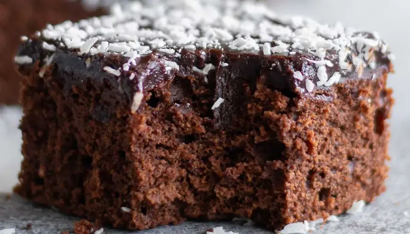 Saftig chokladkaka recept: en bit mörk chokladkaka med chokladglasyr och kokosflingor.