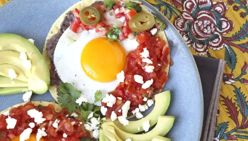 Två huevos rancheros med stekt ägg, svarta bönor, salsa, jalapeños och avokado. En härlig frukost!
