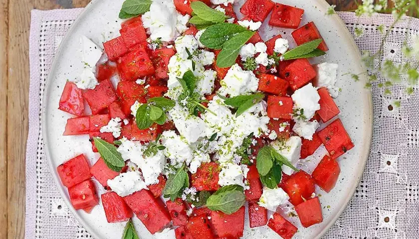 Watermelon and feta salad with mint and lime zest on a white plate.