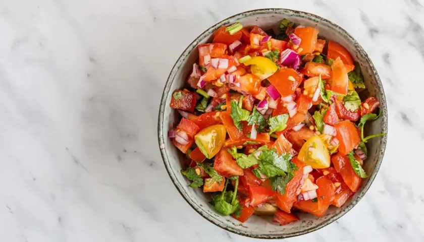 En skål med färsk pico de gallo, full av hackade tomater, rödlök och koriander, redo att serveras.