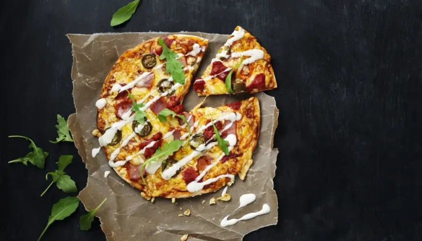 En läcker tortilla pizza med jalapeños, skinka och ruccola, ringlad med vit sås.