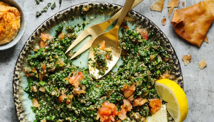 En fräsch tabbouleh med persilja, tomat och bulgur, serverad med citronklyftor och pitabröd. Ett perfekt tabbouleh recept för sommaren.