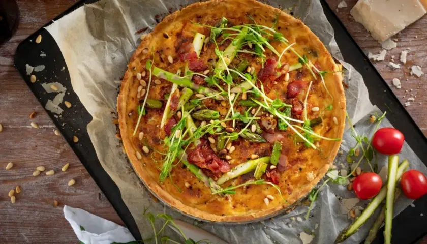 En gyllene sparrispaj med knaprigt bacon, pinjenötter och färska gröna toppar. Perfekt för en vårmåltid.