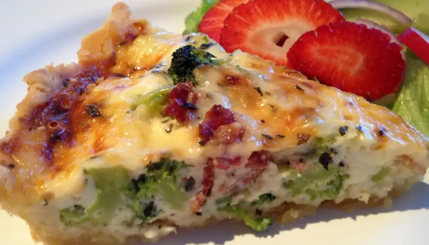 En bit broccoli och baconpaj med en sallad på sidan. Pajen har en gyllene skorpa och fyllning med broccoli och bacon.
