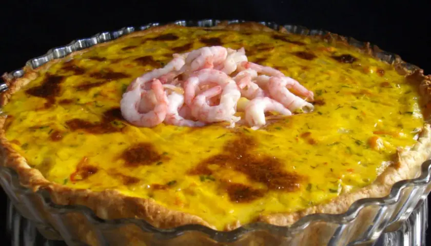 En gyllene räkpaj med en generös topping av saftiga räkor, redo att avnjutas.