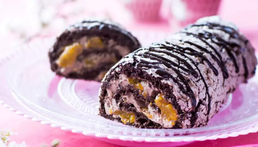 En chokladkaka med aprikosfyllning, perfekt för ett budapestrulle recept. Garnerad med chokladsås och pudersocker.