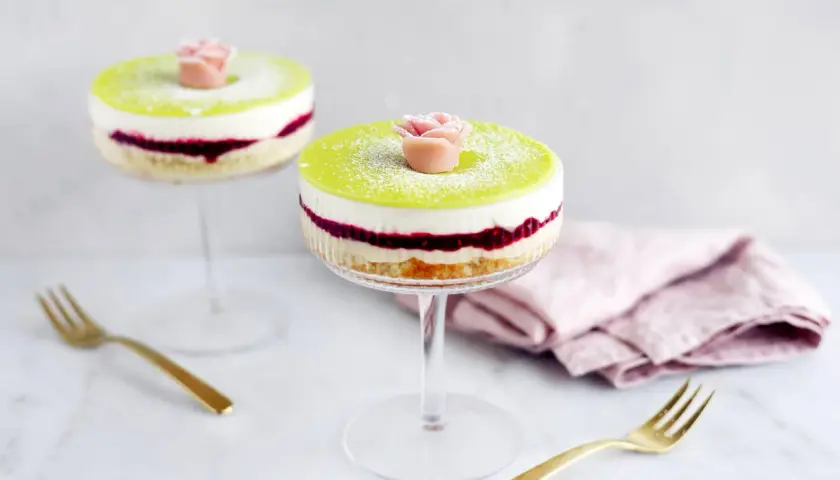 Två vackra prinsesstårtor i glas, dekorerade med en rosa marsipanros och pudrade med florsocker. Perfekt för en festlig fika.