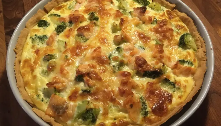 En gyllene laxpaj med broccoli och smält ost, redo att serveras.