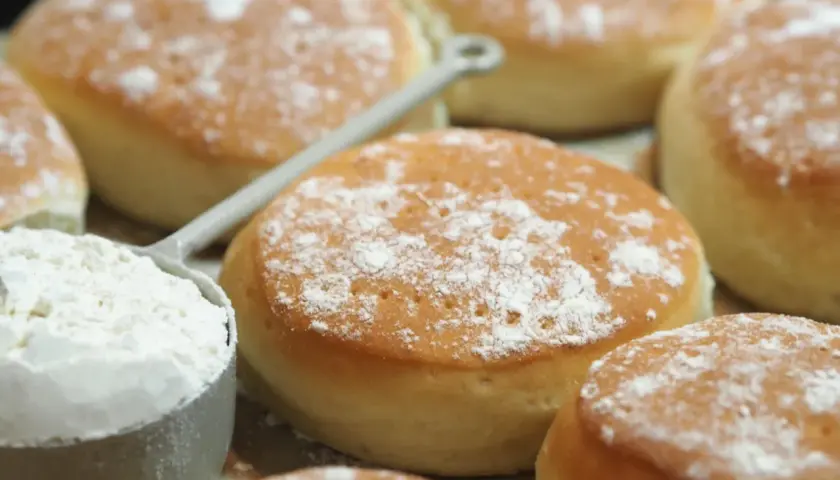 Nybakade tekakor, pudrade med mjöl, redo för ett enkelt tekakor recept. En skopa mjöl syns i förgrunden.