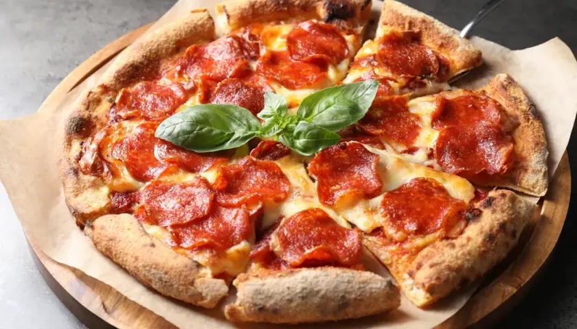 En utsökt pepperoni pizza med smält ost och färsk basilika. Vilken ost till pizza är din favorit?
